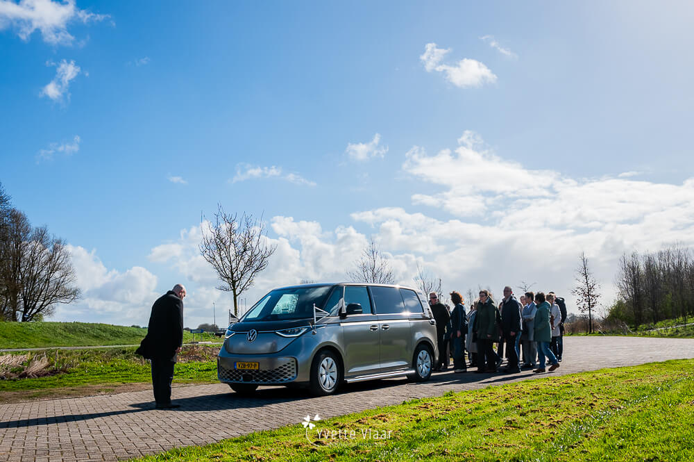 Familie begeleidt een elektrische Volkswagen uitvaartbus tijdens een persoonlijk afscheid, vastgelegd door een uitvaartfotograaf.