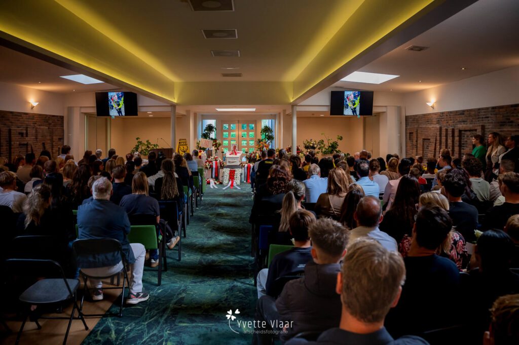 Grote zaal vol met mensen bij een kinderuitvaart vastgelegd door uitvaartfotograaf