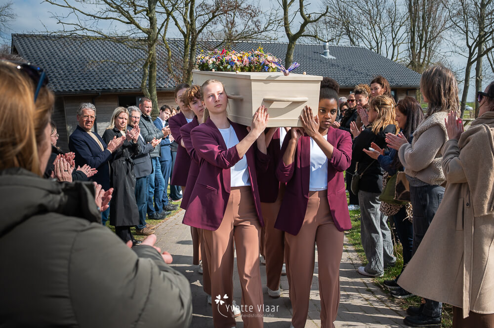 Dragers dragen de kist op schouders op een natuurbegraafplaats vastgelegd door een uitvaartfotograaf