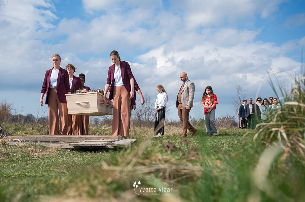 Dragers plaatsen de kist boven het graf op een natuurbegraafplaats vastgelegd door een uitvaartfotograar